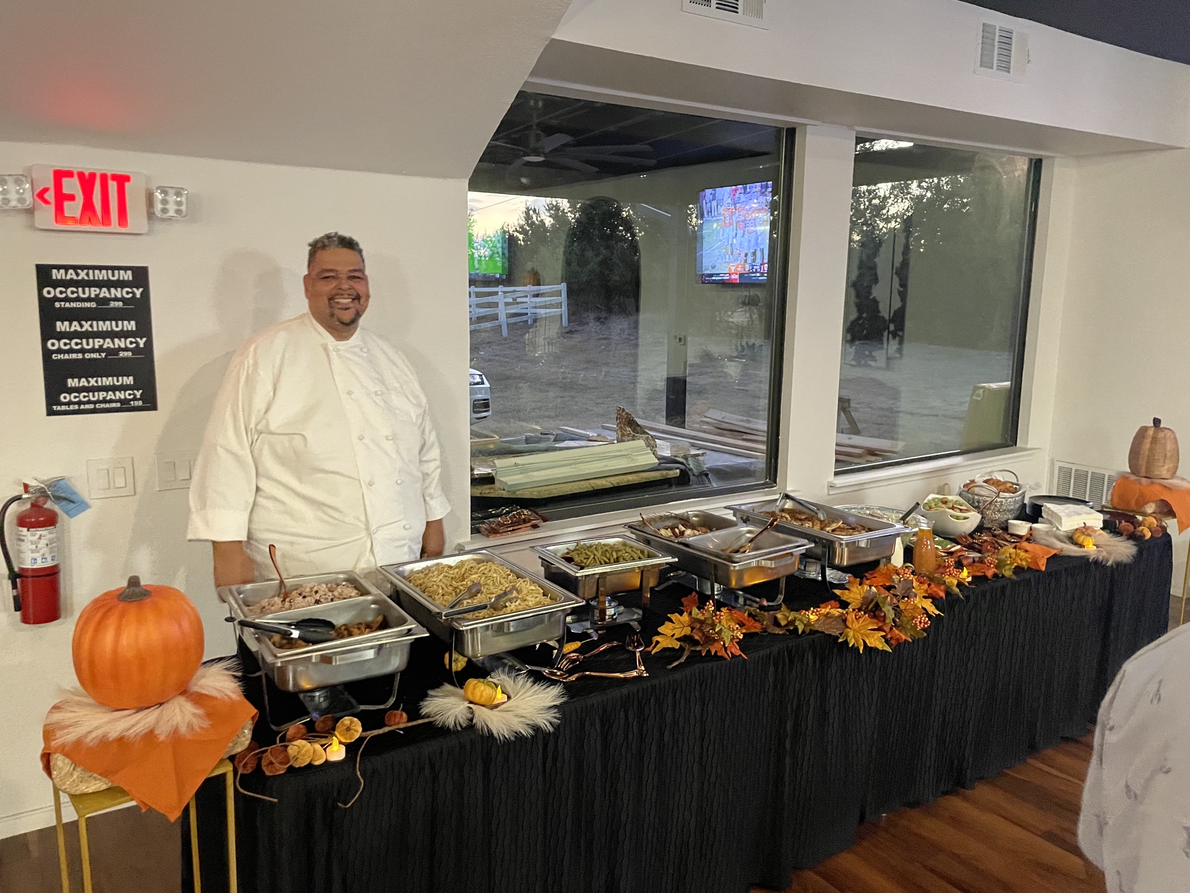 A chef in white standing beside a holiday corporate buffet at the venue.