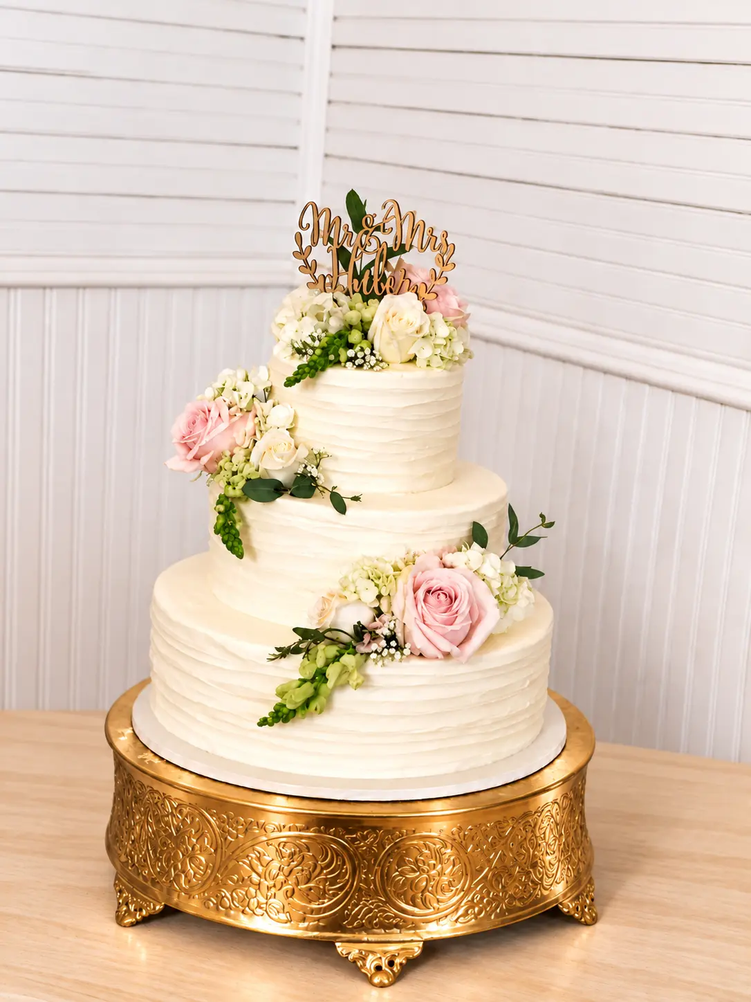 Wedding cake with delicate florals and a gold stand